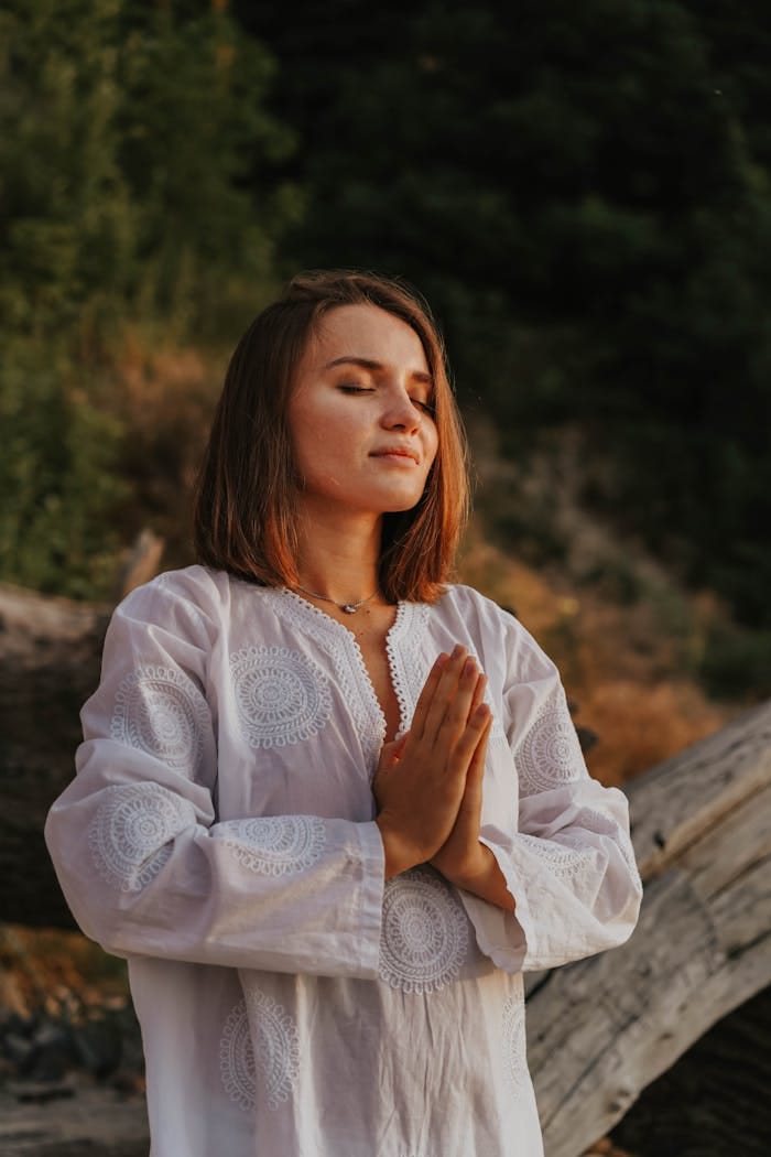 Peaceful woman with closed eyes meditating in nature, embracing mindfulness.